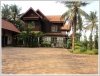 Lao style house with large garden next to rice paddy field